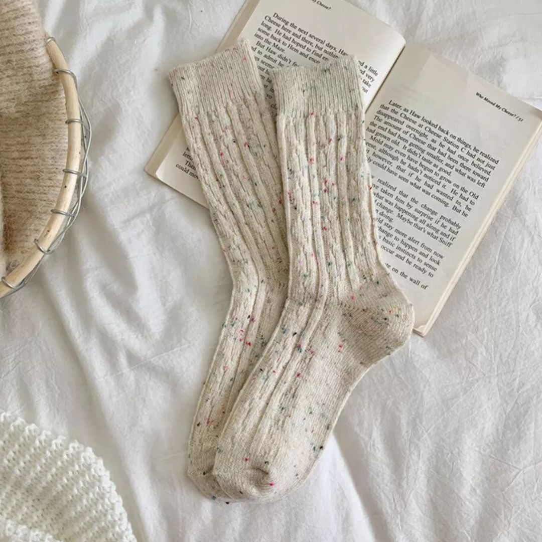 Beige Wollsocken mit bunten Punkten auf offenem Buch, gemütlich, warm, Strickdesign.