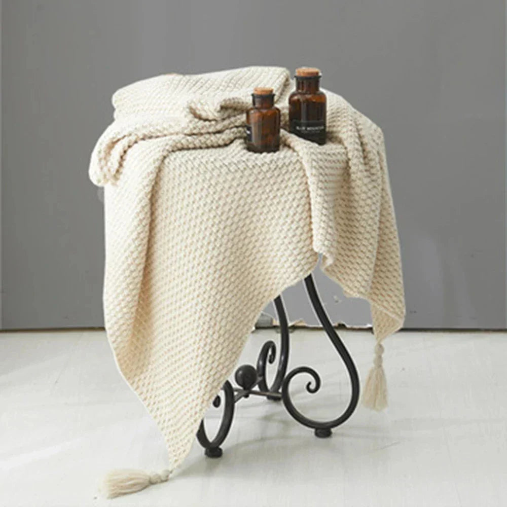 Beige Strickdecke auf Metallhocker, dekoriert mit braunen Glasflaschen, Wohnzimmerdekoration.