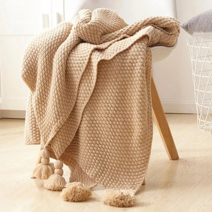 Beige Strickdecke mit Quasten auf Stuhl, gemütlich, Wohnzimmer, Dekoration, Baumwolle.