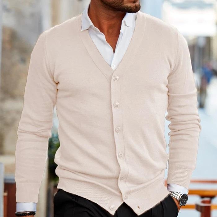 Mann in cremefarbenem Cardigan, V-Ausschnitt, Knopfleiste, eleganter Herrenmode-Look.