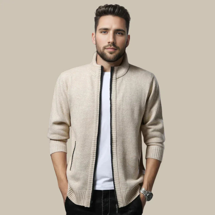 Mann in beigem Strickjacke, weißem T-Shirt, schwarzer Hose; modische Herrenbekleidung.