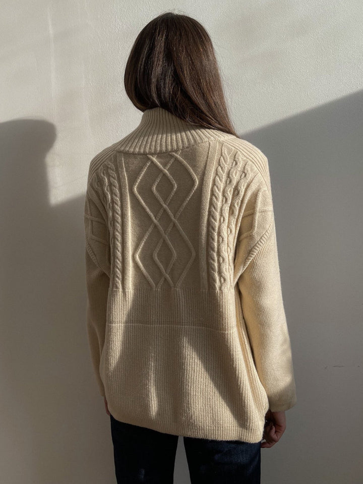Frau in cremefarbenem Strickpullover mit Zopfmuster, Rückansicht, Herbstmode, gemütlich.