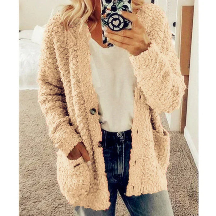 Frau in beigem Strickcardigan, lässiger Stil, Handyhülle mit Muster, gemütliches Outfit.