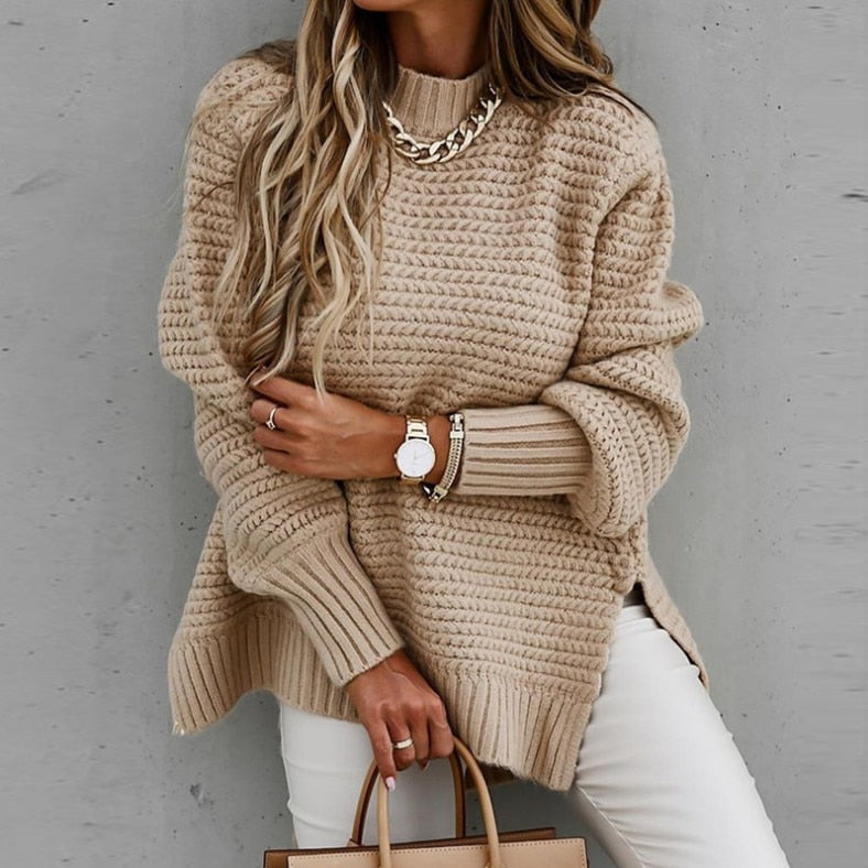Frau in beigem Strickpullover, goldene Kette, weiße Hose, modisch, elegant, Herbstmode.