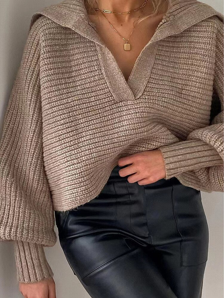 Frau in beigem Strickpullover und schwarzer Lederhose, modischer Herbstlook.