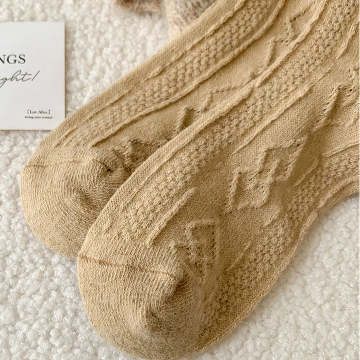 Beige Stricksocken aus Baumwolle mit Zopfmuster auf weißem Hintergrund, gemütliche Wintermode.