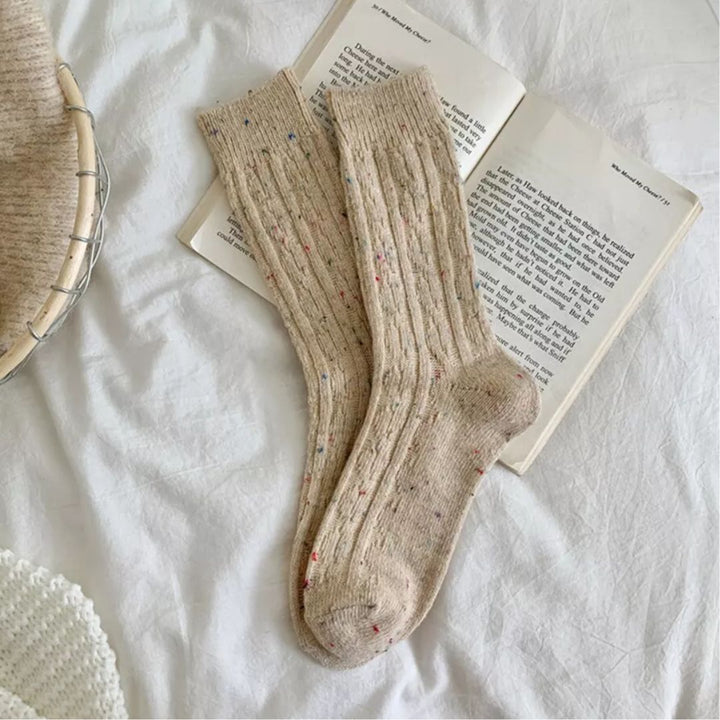 Beige Wollsocken auf einem offenen Buch, gemütlich, warm, gestrickt, ideal für kalte Tage.