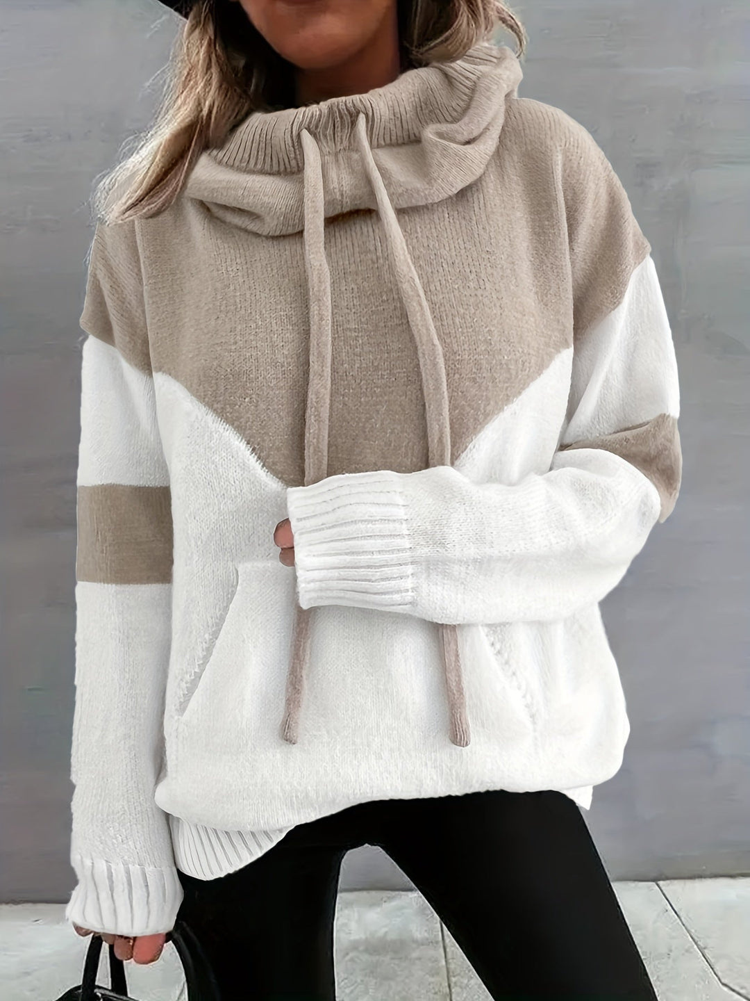 Frau in beige-weißem Strickpullover mit Kapuze, Kordeln und Taschen, modisch, gemütlich.