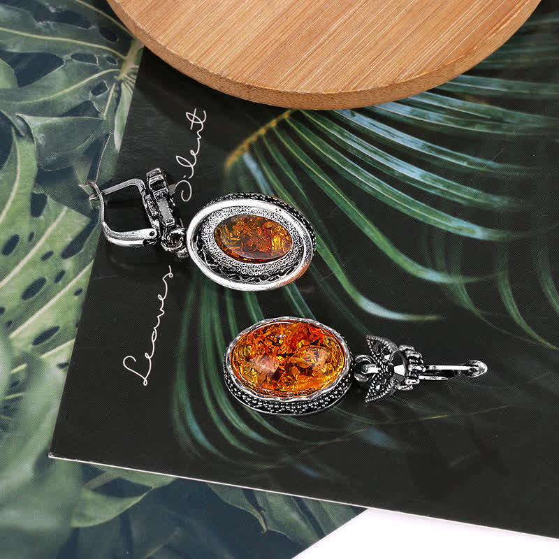 Silberne Ohrringe mit Bernstein, oval, Vintage-Stil, auf tropischem Hintergrund.