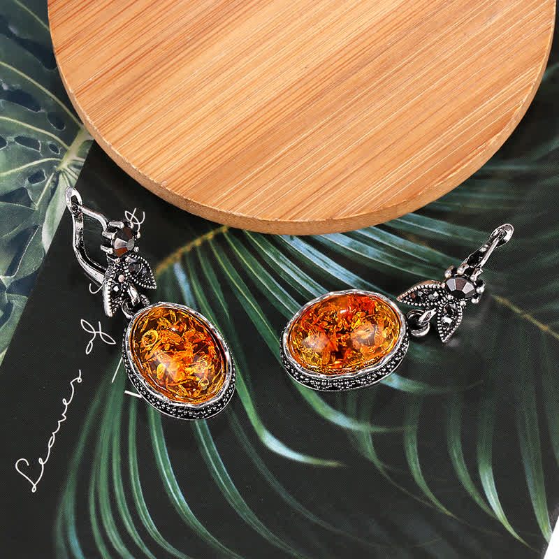 Silberne Ohrringe mit Bernstein, florales Design, eleganter Schmuck, auf Holz- und Blattuntergrund.