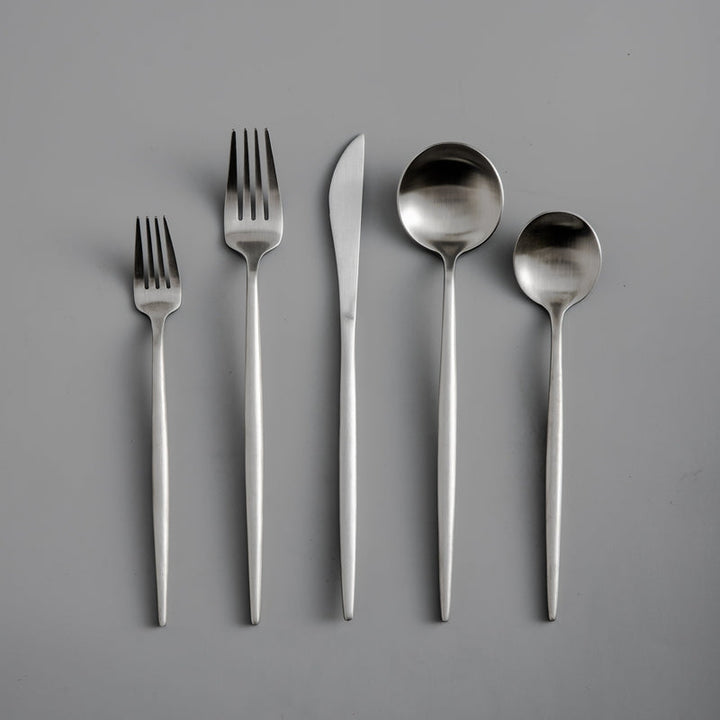 Fünfteilige Edelstahl-Besteckset, bestehend aus Gabeln, Messer, Löffeln auf grauem Hintergrund.