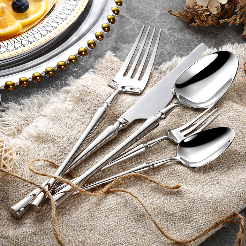 Elegantes Edelstahl-Besteckset auf Leinentuch, bestehend aus Gabeln, Messer und Löffeln.