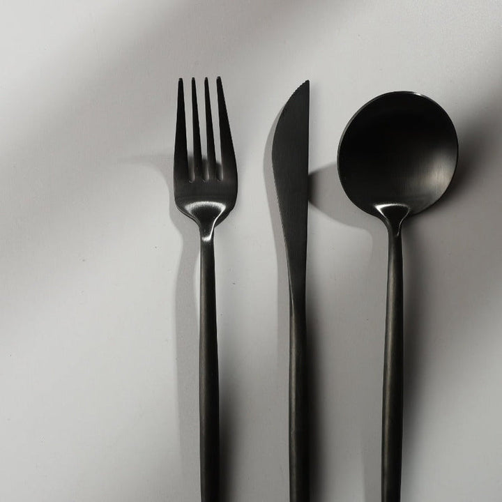 Minimalistisches Besteckset aus Edelstahl, bestehend aus Gabel, Messer und Löffel, modern.