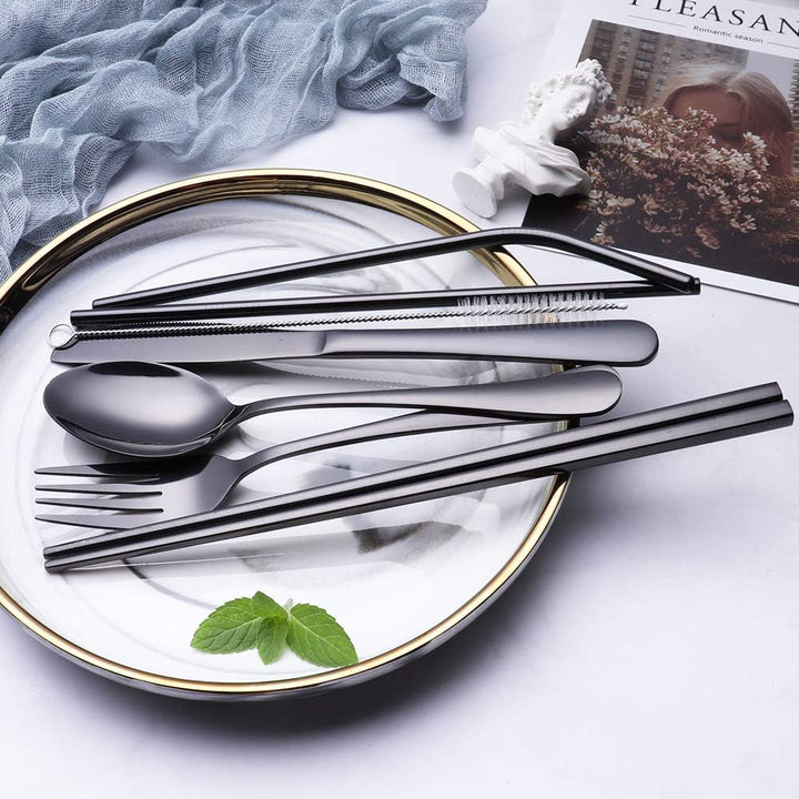 Schwarzes Edelstahl-Besteckset auf Teller, inklusive Löffel, Gabel, Strohhalm, Bürste, Essstäbchen.