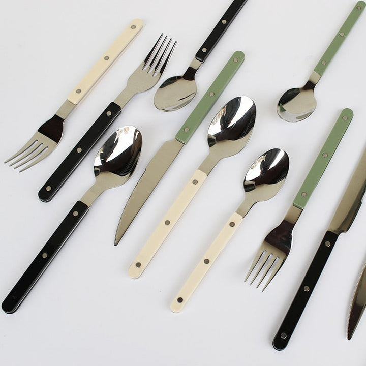 Besteckset aus Edelstahl mit schwarzen, weißen und grünen Griffen, modern, stilvoll, langlebig.