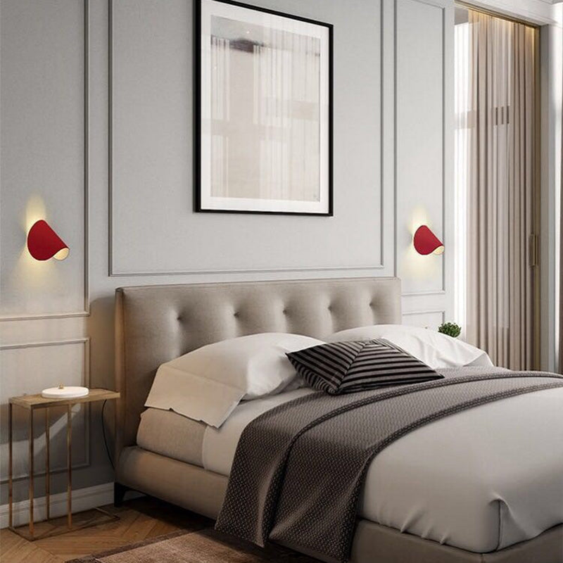 Modernes Schlafzimmer mit grauem Polsterbett, roten Wandleuchten und stilvollem Wandbild.