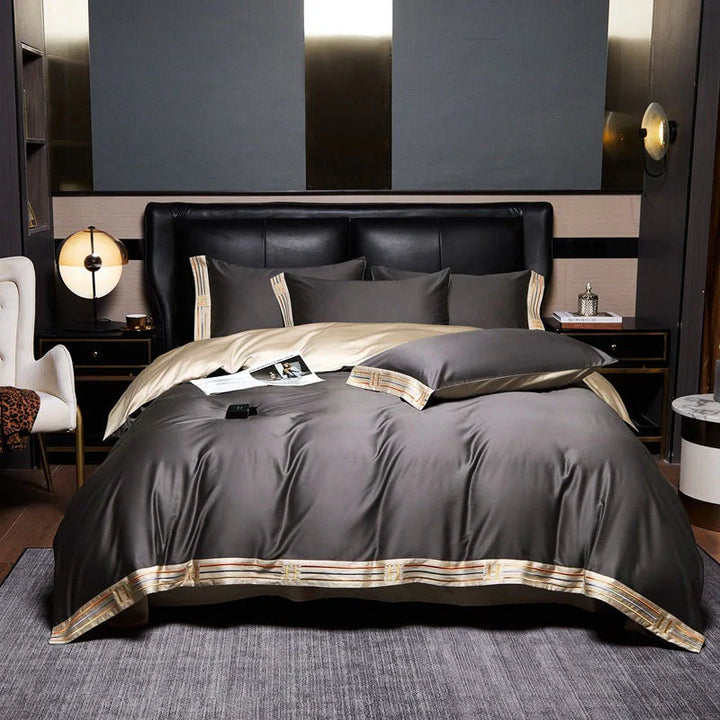Luxuriöse graue Bettwäsche-Set aus Satin mit goldenen Akzenten auf einem modernen Doppelbett.