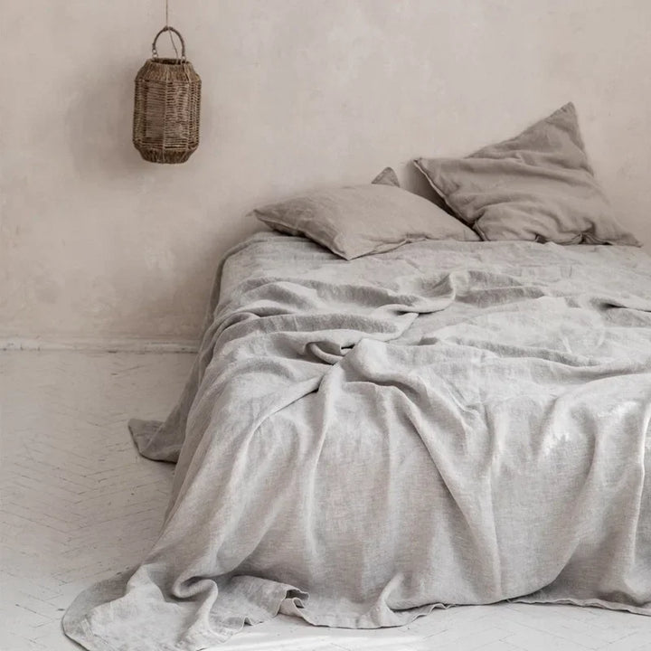 Graues Leinenbettwäsche-Set auf Bett mit Kissen, rustikaler Stil, Schlafzimmer-Dekoration.