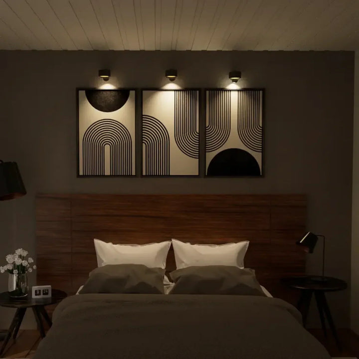 Moderne Schlafzimmerbeleuchtung über Doppelbett mit abstrakter Wandkunst, Holzverkleidung.