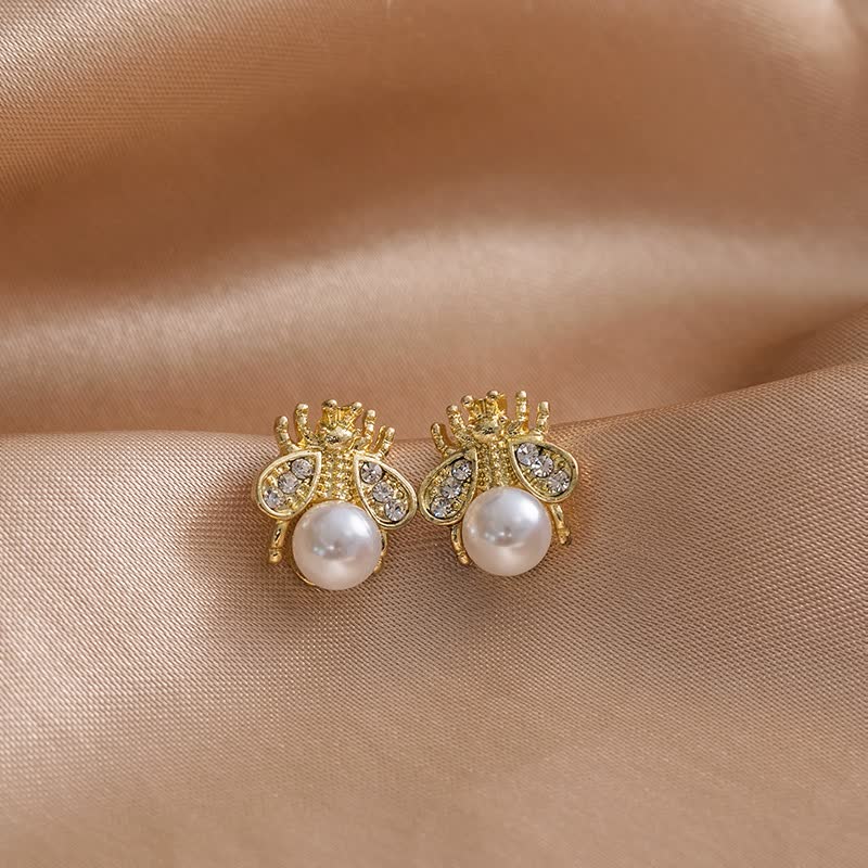 Goldene Bienen-Ohrringe mit Perlen und Strasssteinen auf Seide, eleganter Schmuck.