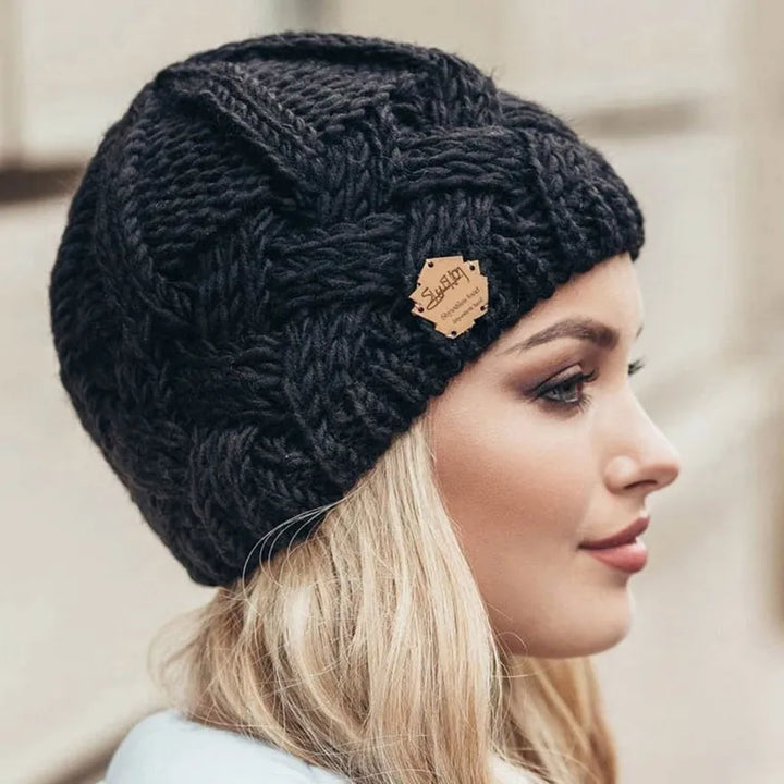 Frau mit schwarzer Strickmütze, Zopfmuster, Lederetikett, Wintermode, Damenaccessoire.