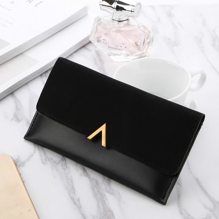 Schwarze Lederhandtasche mit goldener Schnalle auf Marmortisch, elegantes Damenaccessoire.