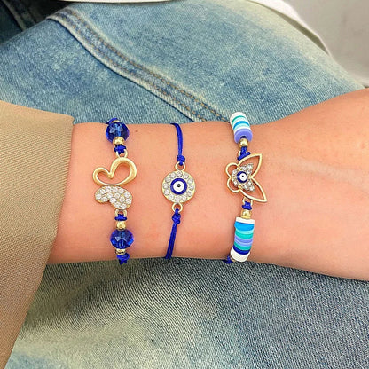 Drei blaue Armbänder mit goldenen Anhängern und Perlen auf einem Handgelenk, modisch und elegant.