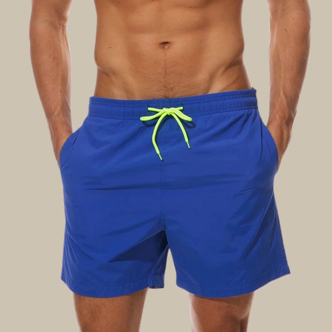 Mann in blauer Badehose mit neon-grünem Kordelzug, Strandmode, Sommerbekleidung.