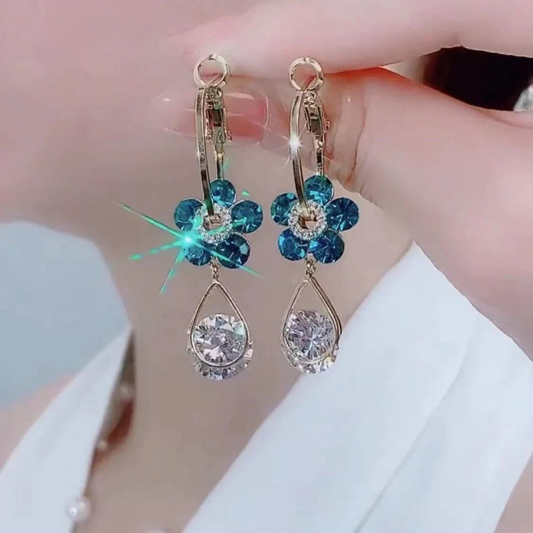 Goldene Ohrringe mit blauen Blumen und klaren Kristallen, eleganter Schmuck für Damen.
