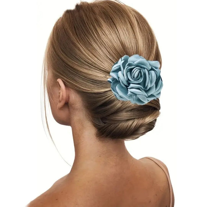 Frau mit blonder Hochsteckfrisur und blauer Stoffblume als Haarschmuck.