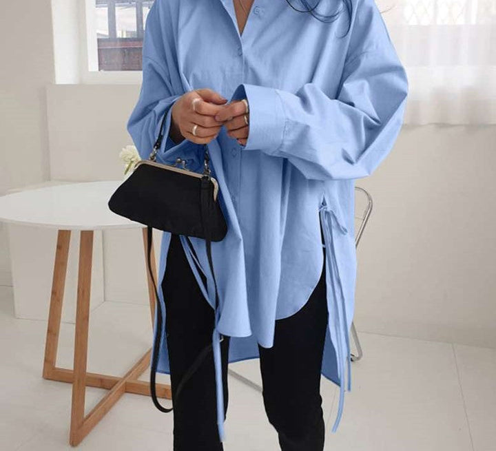 Frau in blauer Oversize-Bluse, schwarze Tasche, moderne Mode, lässiger Stil, Innenraum.