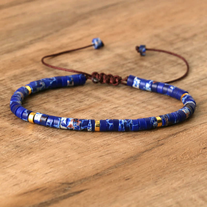 Blaues Perlenarmband aus Naturstein auf Holzoberfläche, verstellbar, handgefertigt.