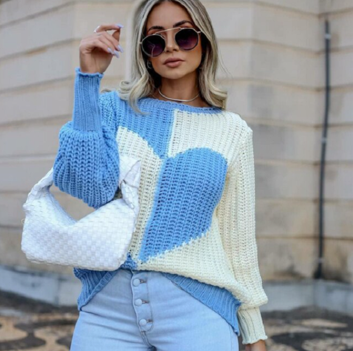Frau in blau-weißem Herzpullover, Sonnenbrille, weiße Tasche, modisch, urbaner Hintergrund.