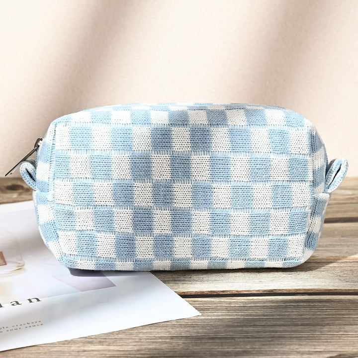 Hellblau-weiß karierte Kosmetiktasche aus Stoff, rechteckig, Reißverschluss, auf Holztisch.