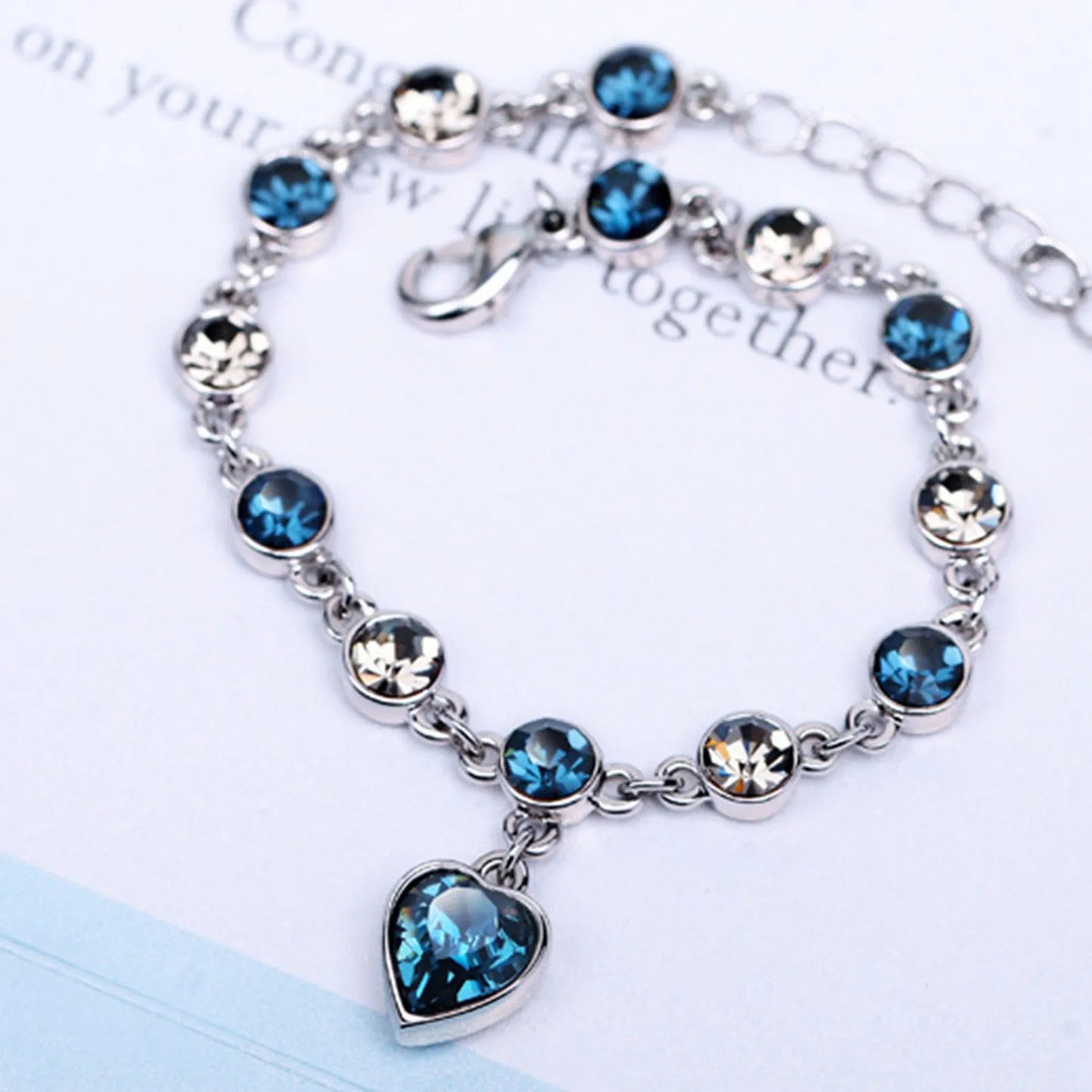 Silberarmband mit blauen und klaren Kristallen, Herzanhänger, eleganter Schmuck, Damenaccessoire.