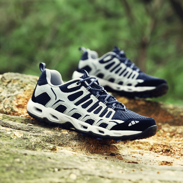 Blau-weiße Outdoor-Sportschuhe auf Felsen, atmungsaktiv, rutschfest, ideal für Wandern.