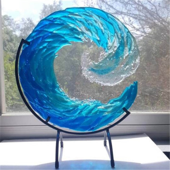 Blaue Glaswelle Skulptur auf schwarzem Ständer, dekorative Kunst für Zuhause, Fensterhintergrund.