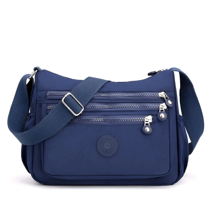 Blaue Umhängetasche mit Reißverschlüssen, verstellbarem Gurt, ideal für Damen, Nylonmaterial.