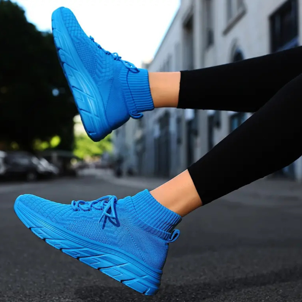 Blaue Sportschuhe, gestricktes Material, Straßenhintergrund, bequeme Laufschuhe, Damenmode.