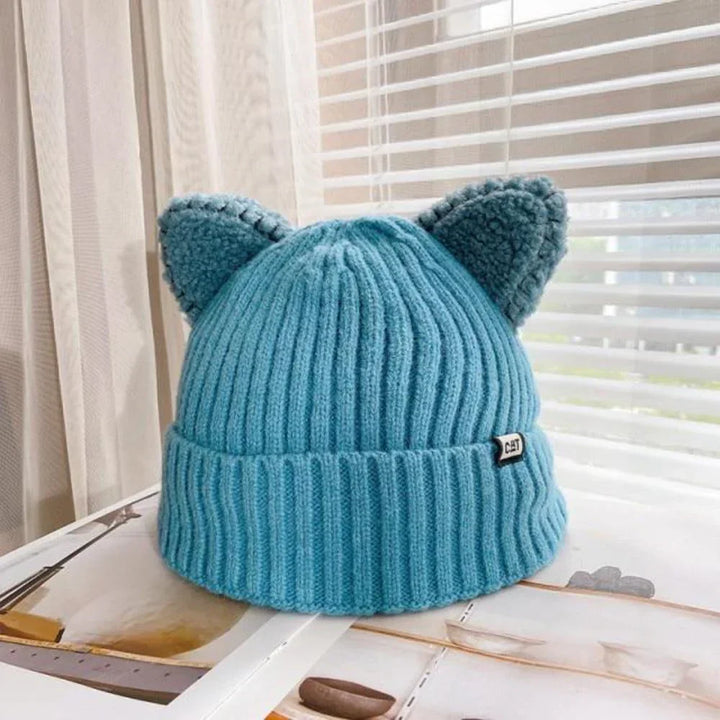 Blaue Strickmütze mit Katzenohren, Wintermode, warm, gemütlich, Damenaccessoire, Fensterbank.