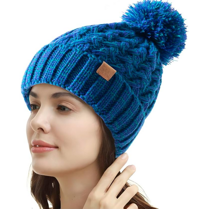 Frau mit blauer Strickmütze, Bommel, Zopfmuster, Wintermode, Damenaccessoire.