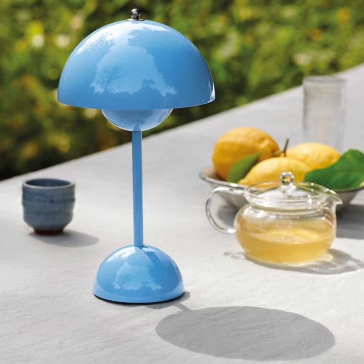 Blaue Tischlampe im Freien, modernes Design, neben Tee und Zitronen auf Tisch.