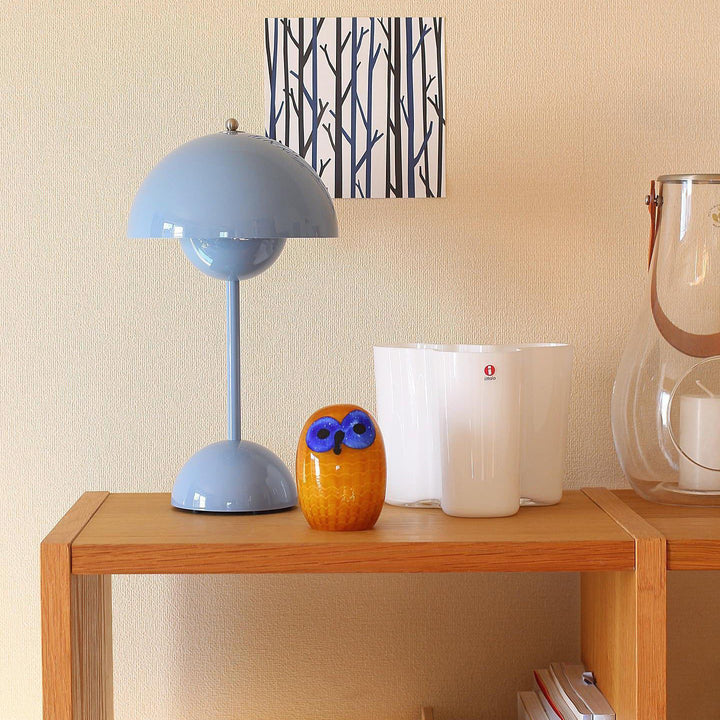 Blaue Tischlampe, gelbe Eulenfigur, weiße Vasen auf Holzregal, modernes Dekor, Wohnzimmer.