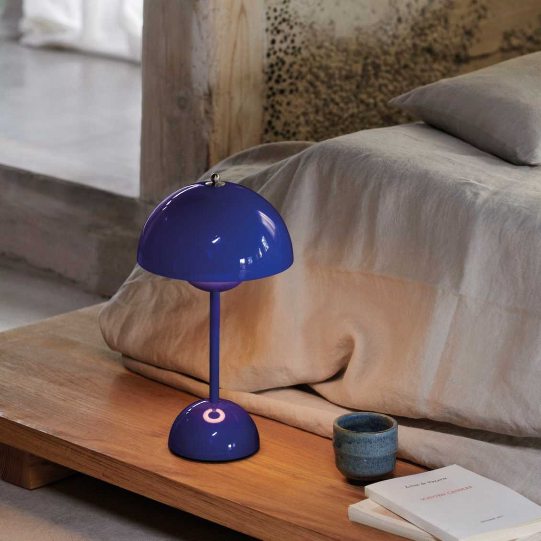 Blaue Tischlampe auf Holztisch neben Bett, modernes Design, Schlafzimmerdekoration.