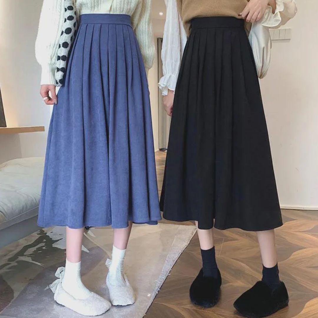 Zwei Frauen in blauen und schwarzen Faltenröcken, modische Winterkleidung, Innenraum.