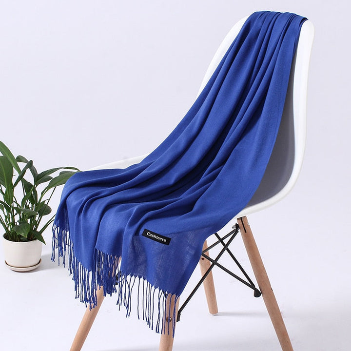 Blaue Kaschmirdecke auf weißem Stuhl, weiches Material, Fransen, luxuriöses Wohnaccessoire.