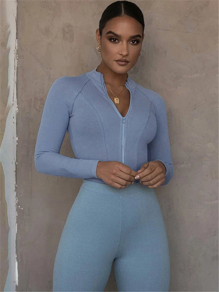 Frau in hellblauem Sportanzug, Reißverschluss, langärmelig, elegantes Design, Fitnessmode.