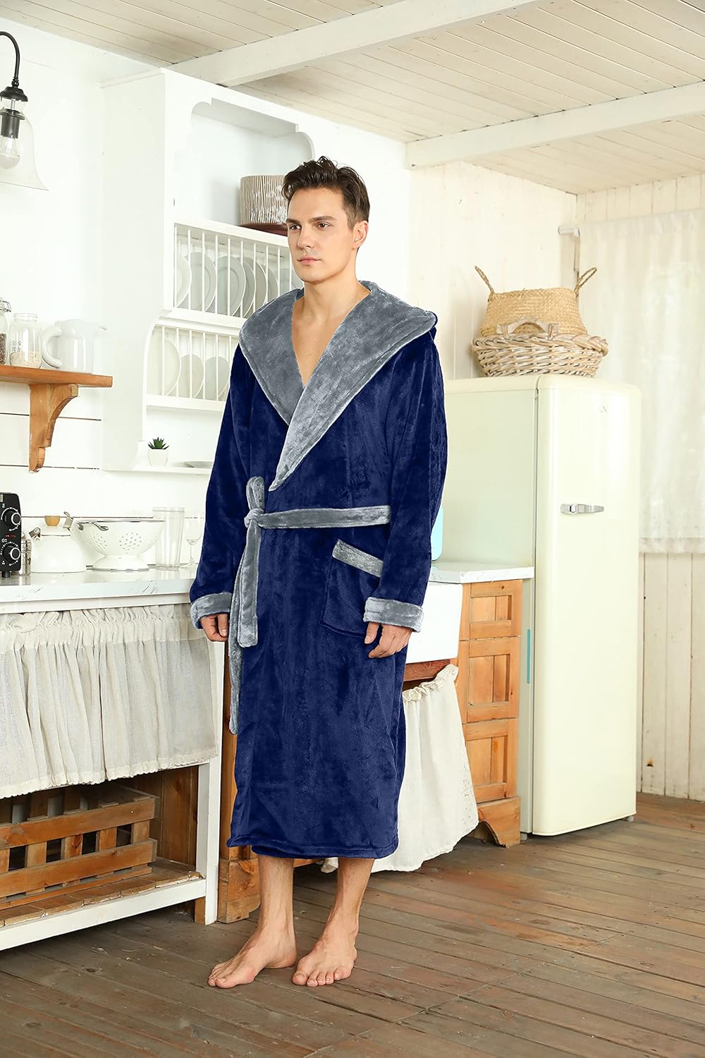 Mann im blauen Fleece-Bademantel mit grauem Kragen in rustikaler Küche.