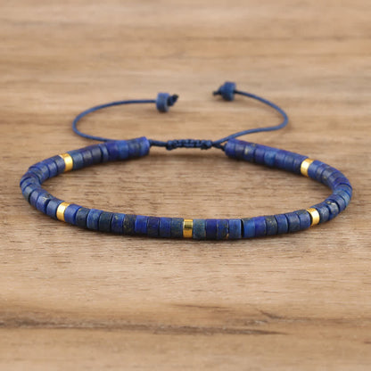 Blaues Lapis-Lazuli-Armband mit goldenen Akzenten, verstellbar, auf Holzoberfläche.