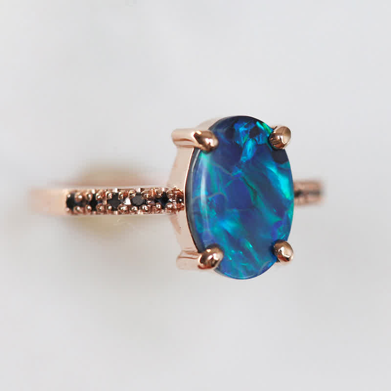 Opalring aus Roségold mit blauem Opal und kleinen schwarzen Diamanten, eleganter Schmuck.